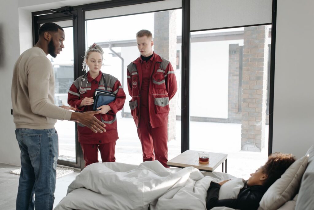 Paramedics attending to a patient indoors, discussing the situation in modern home setting.